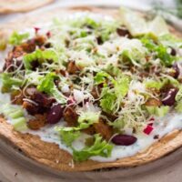 chorizo tostadas with beans on a wooden board.