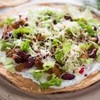 chorizo tostadas with beans on a wooden board.