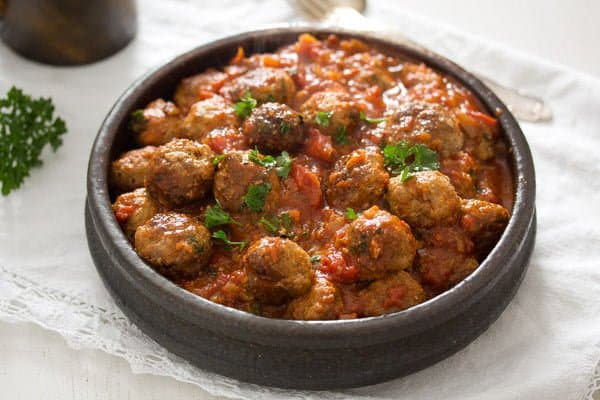 serving spanish meatballs in a small brown bowl.