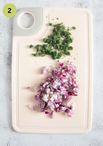 finely chopped red onions and dill on a cutting board.