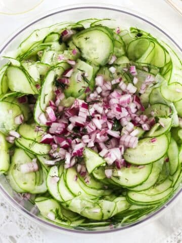 oil and vinegar cucumber salad with chopped red onions on top.
