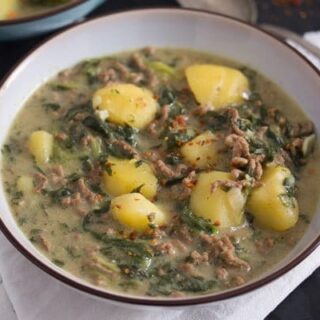 beef and potato curry cooked with spinach and yogurt served in a bowl