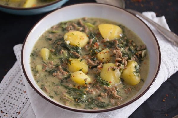 beef and potato curry cooked with spinach and yogurt served in a bowl