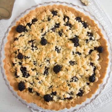 golden blackberry crumble pie on a serving platter.
