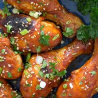 baked drumsticks with honey and soy sauce on a blue plate.