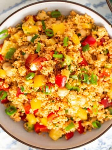 curried couscous salad with chickpeas, green onions and peppers in a bowl.