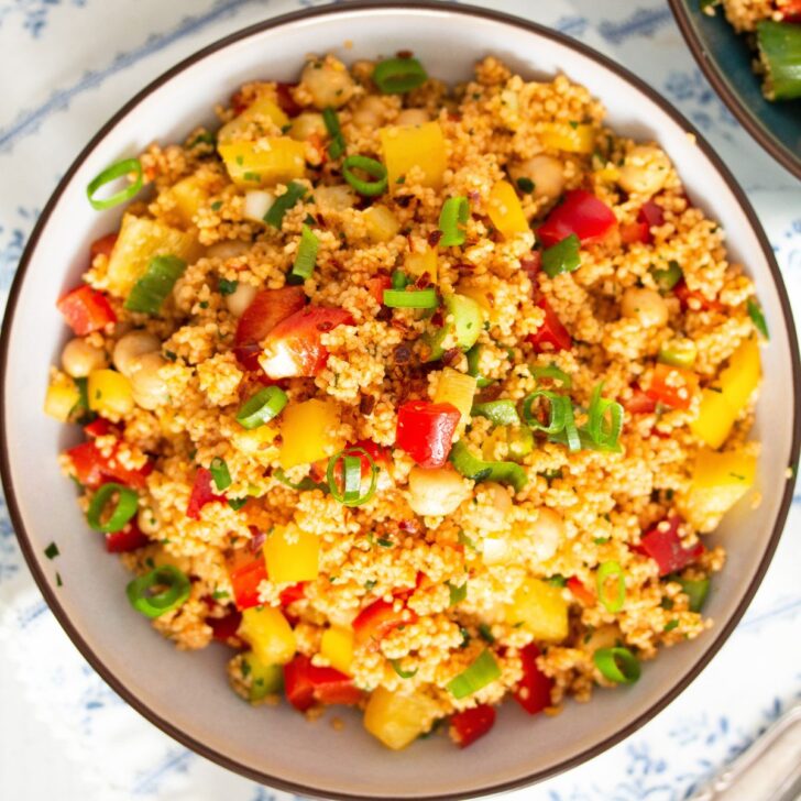 curried couscous salad with chickpeas, green onions and peppers in a bowl.