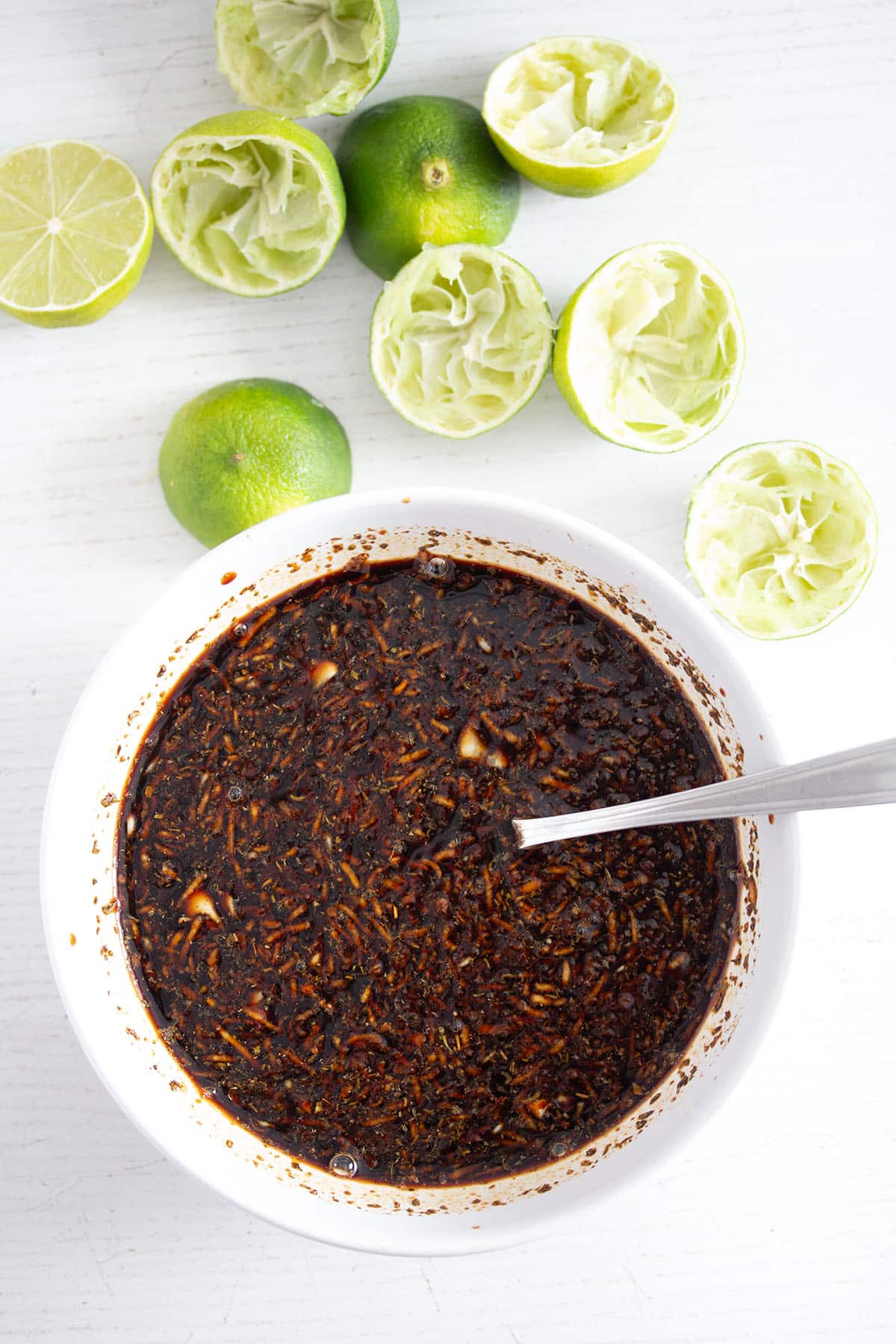 honey lime marinade for chicken in a small bowl and juiced limes around it.
