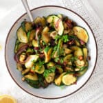 bowl with sauteed zucchini and onions with a spoon in it.