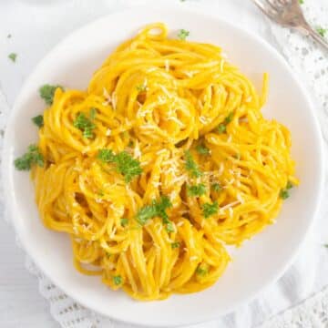 overhead view of a plate with bright yellow hokkaido pumpkin sauce on pasta.