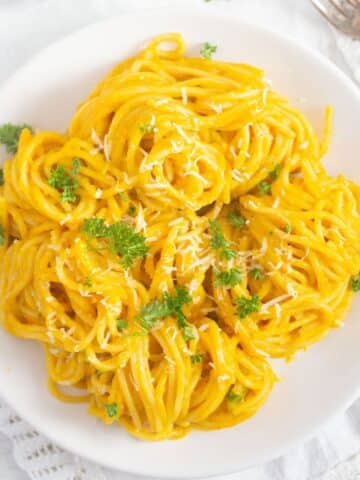 overhead view of a plate with bright yellow hokkaido pumpkin sauce on pasta.