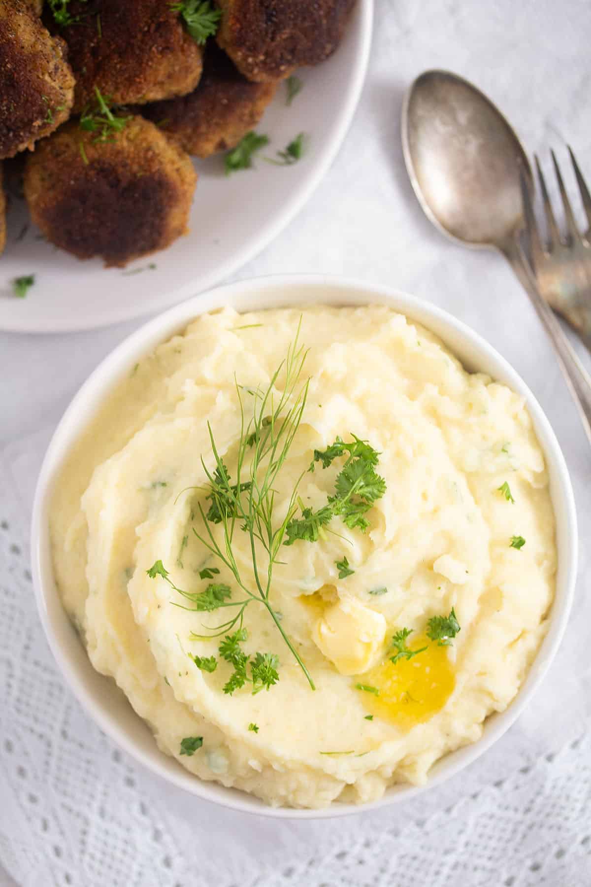 two bowls: one full of mashed potatoes and one with meatballs in it.