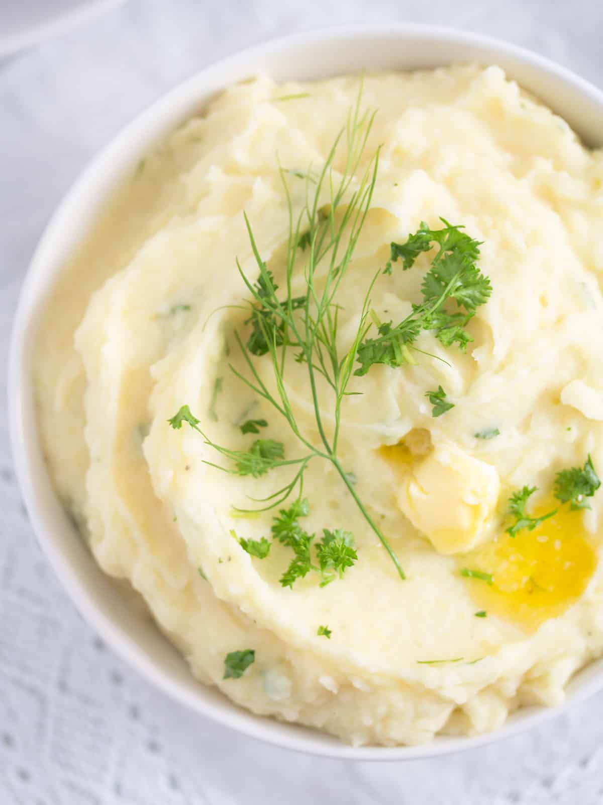close up creamy mashed potatoes with parmesan and roasted garlic with a piece of butter melting on top.
