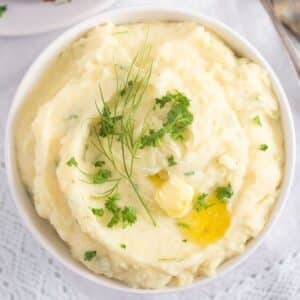 garlic parmesan mashed potatoes with herbs and melting butter on top.