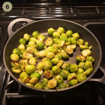 cooking brussels sprouts with sliced garlic in a frying pan.