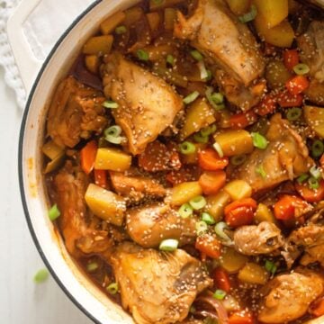 overhead view of a pot full of chicken thighs, potatoes and carrots.