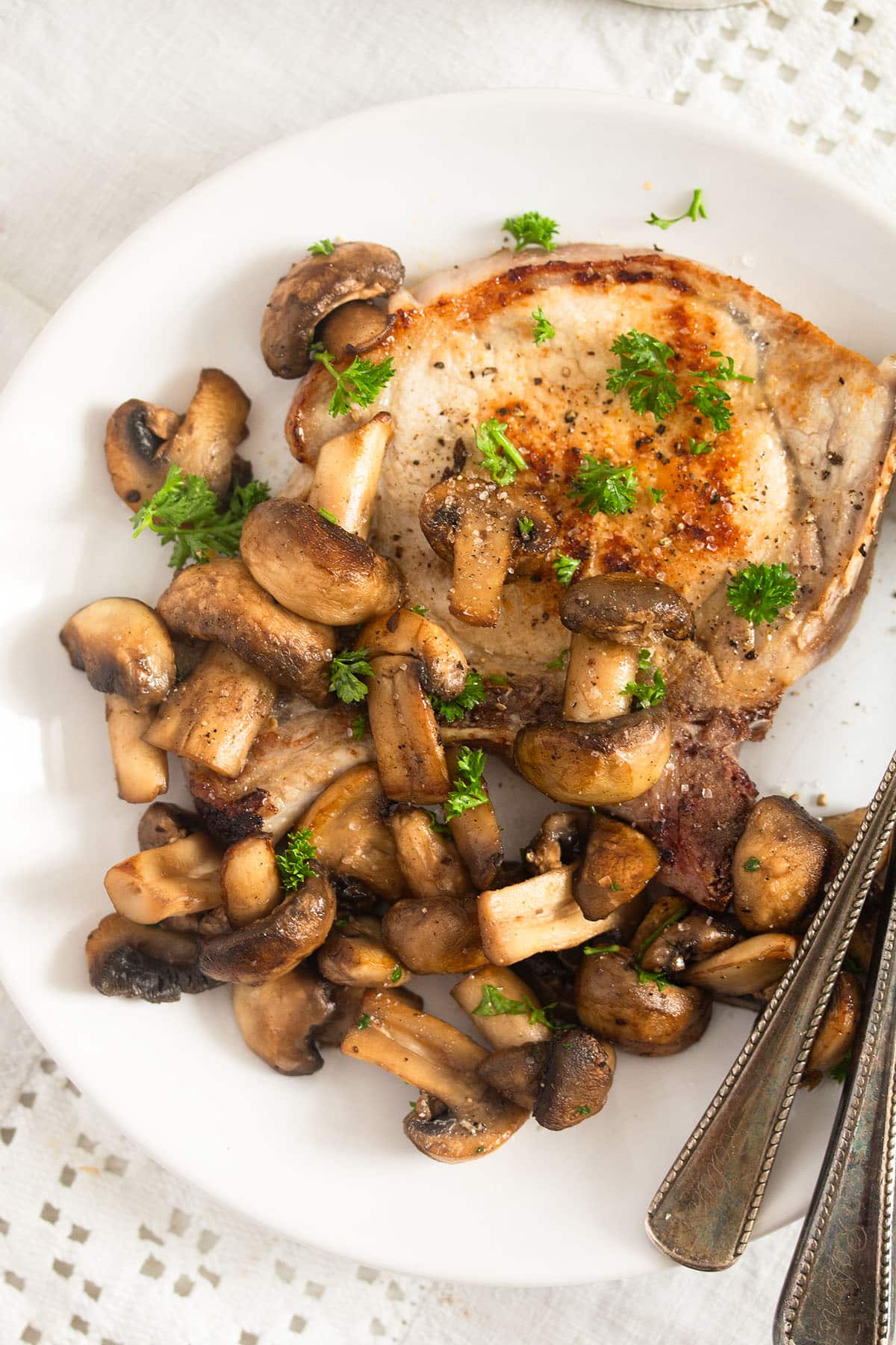 steak and sauteed mushrooms on a white plate.