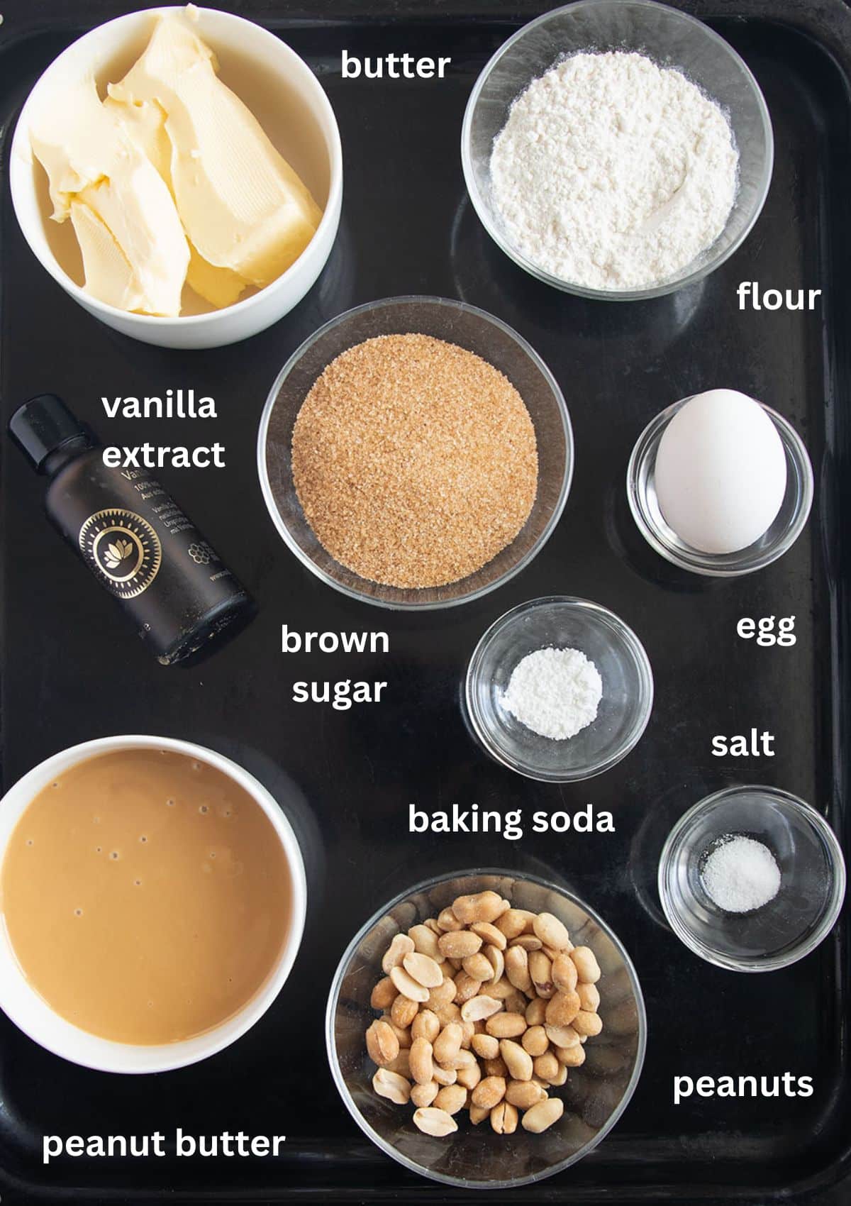 labeled ingredients for making cookies with peanuts, peanut butter, brown sugar, butter, and egg.