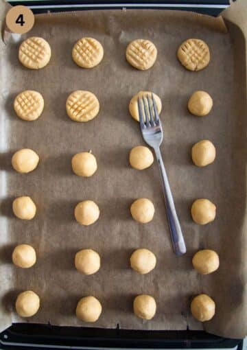 pressing a criss cross pattern on raw cookies with a fork on a lined baking sheet.