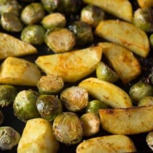 roasted brussels sprouts and potatoes close up on a baking sheet.