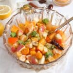 christmas fruit salad in a bowl with lemon pieces and spices around it.