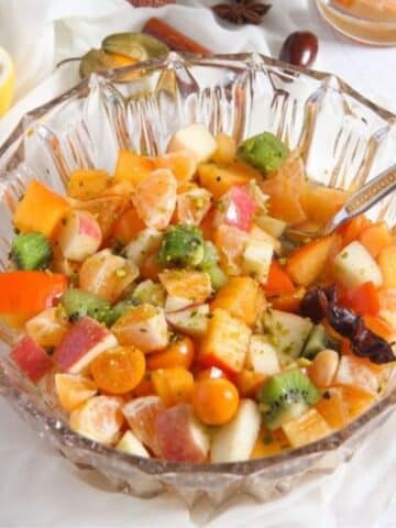 christmas fruit salad in a bowl with lemon pieces and spices around it.