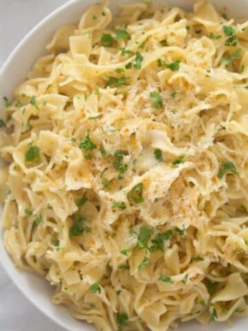 garlic parmesan butter noodles in a bowl sprinkled with parsley.