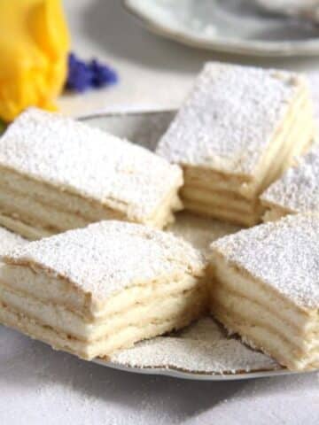 pieces of layered romanian lemon cake on a small plate.