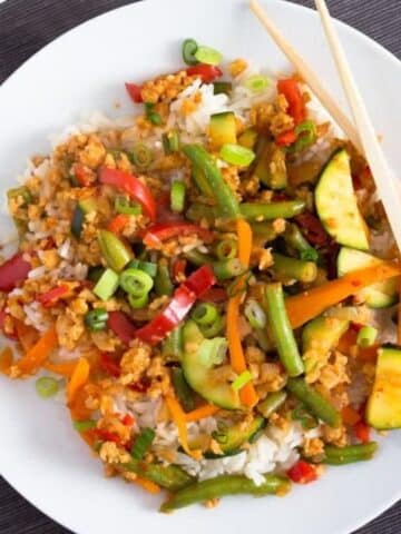 soya granules recipe with lots of vegetables served with rice on a white plate.