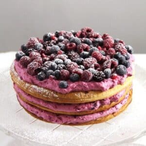 puff pastry cake with pink filling and many sugared berries on top.