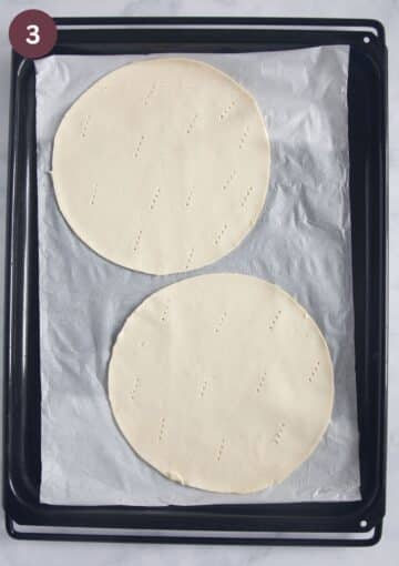 two unbaked puff pastry circles on a lined baking sheet.
