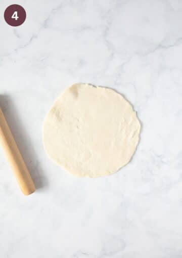one rolled circle of puff pastry and a small rolling pin on the working surface.