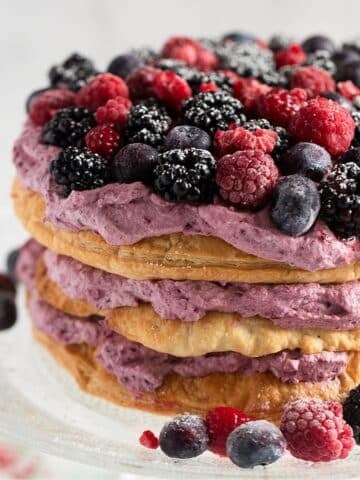 puff pastry cake layered with berry whipped cream and topped with fresh blueberries, blackberries and raspberries.