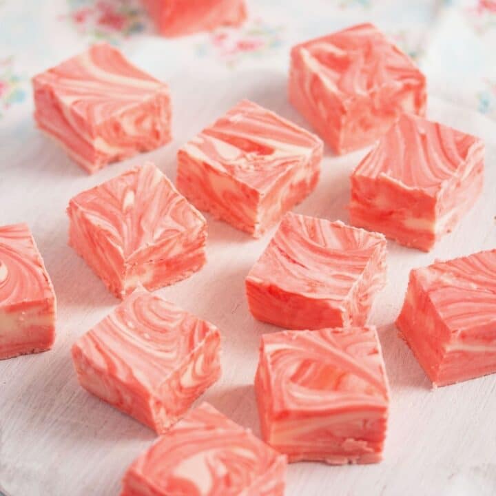 cubes of strawberry fudge with marshmallow fluff on a white cutting board.