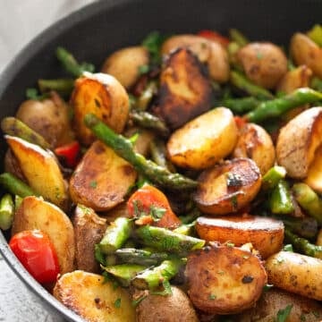 colorful mix of fried potato halves, asparagus stalks and bits of tomatoes.