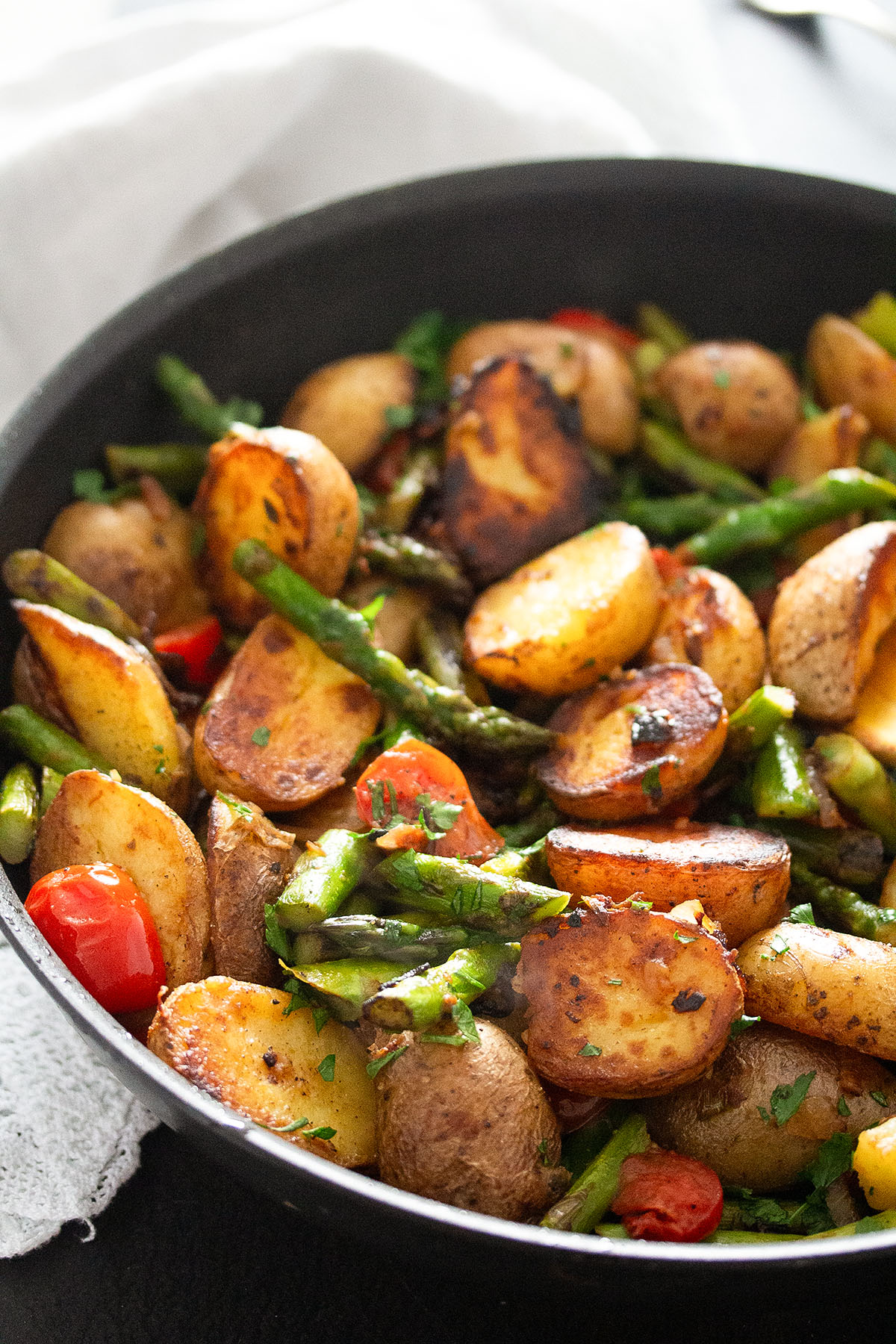 colorful mix of fried potato halves, asparagus stalks and bits of tomatoes. 