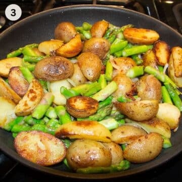 cooking small halved potatoes with asparagus pieces in a skillet.