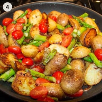 cooking halved potatoes, tomatoes and asparagus on the stove.