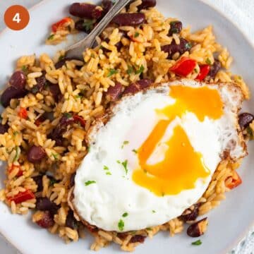 a plate with rice and beans with a runny fried egg on top.