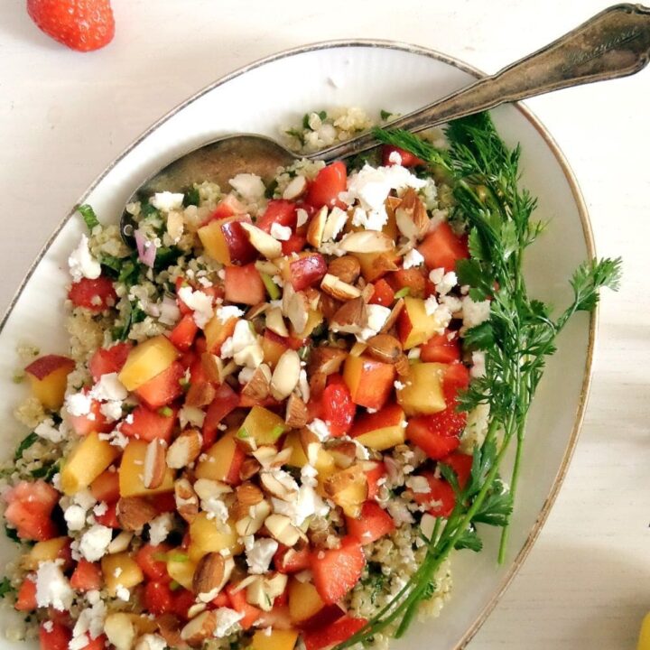 fruit quinoa salad with herbs on a platter with a spoon