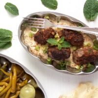 turkish meat rolls with yogurt sauce on a plate.