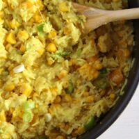 yellow rice with vegetables in a black pot with a spoon