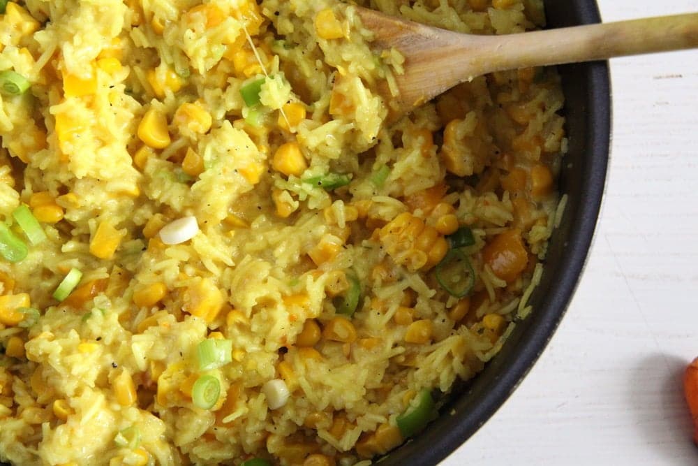 yellow rice with vegetables in a black pot with a spoon
