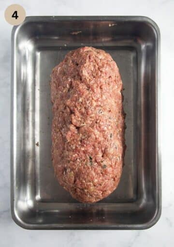 shaped raw meatloaf in a roasting tin before baking.