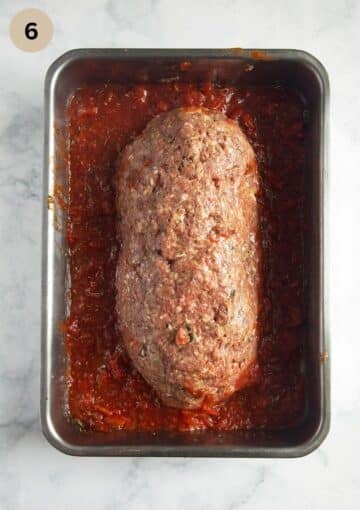 unbaked romanian meatloaf on tomato sauce in a baking dish.