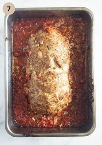 baked meatloaf with eggs on tomato sauce in a roasting tin.