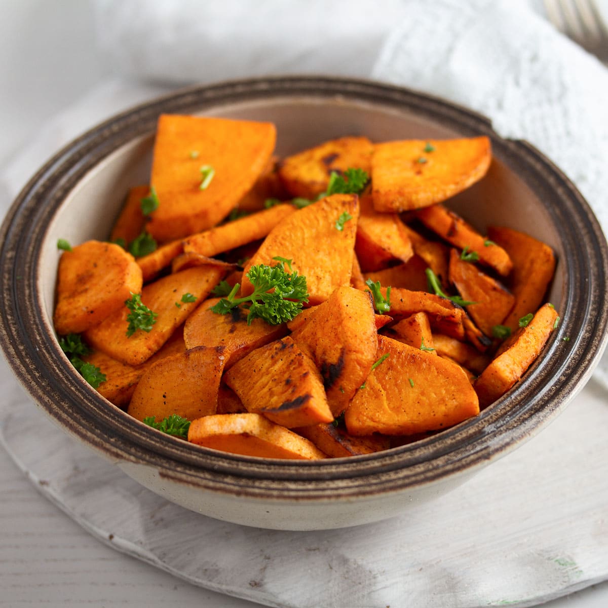 small bowl with sweet potatoes slices sprinkled with parsley.
