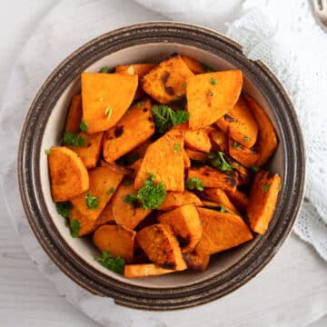 pan-fried sweet potatoes sprinkled with parsley in a small bowl.