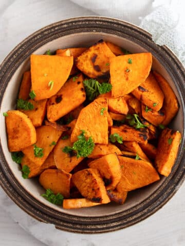pan-fried sweet potatoes sprinkled with parsley in a small bowl.