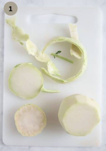 peeling a kohlrabi on a cutting board.